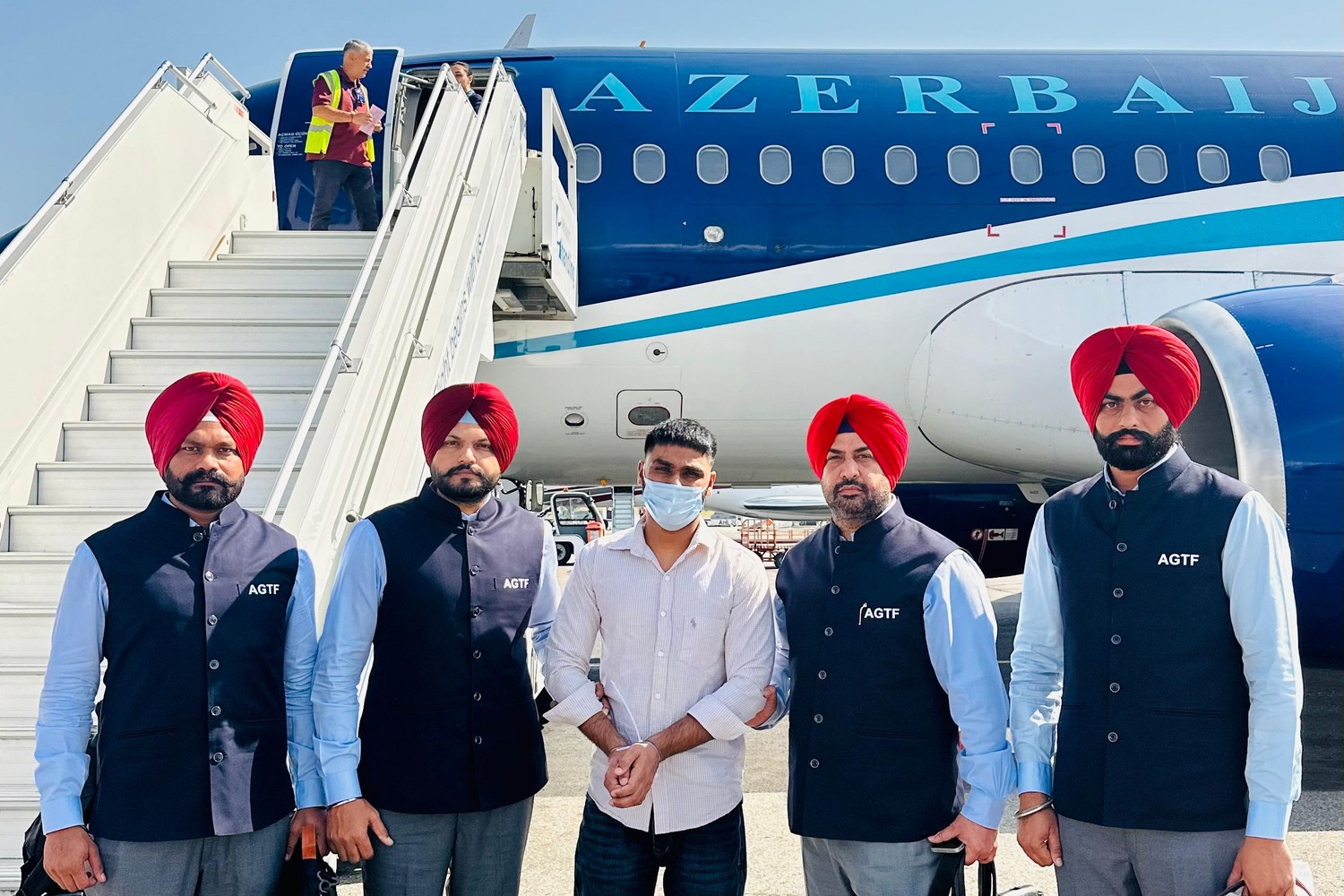 Punjab Police Anti-Gangster Task Force officers with the extradited suspect beside an aircraft