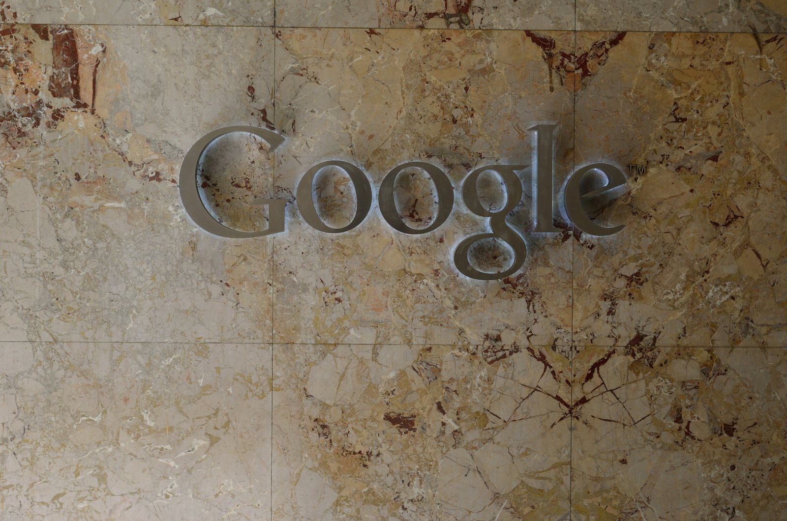 The Google wordmark in metal lettering on a marble wall at a Google office