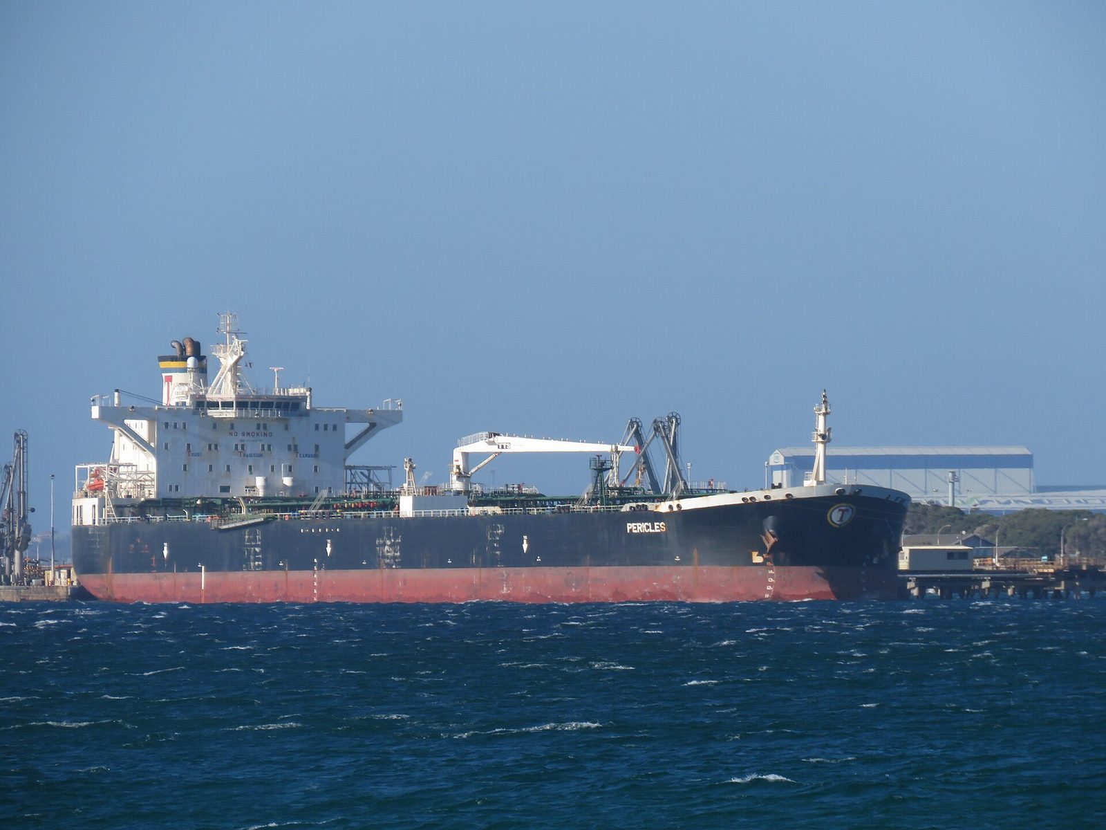 A crude oil tanker on the water alongside a refinery jetty